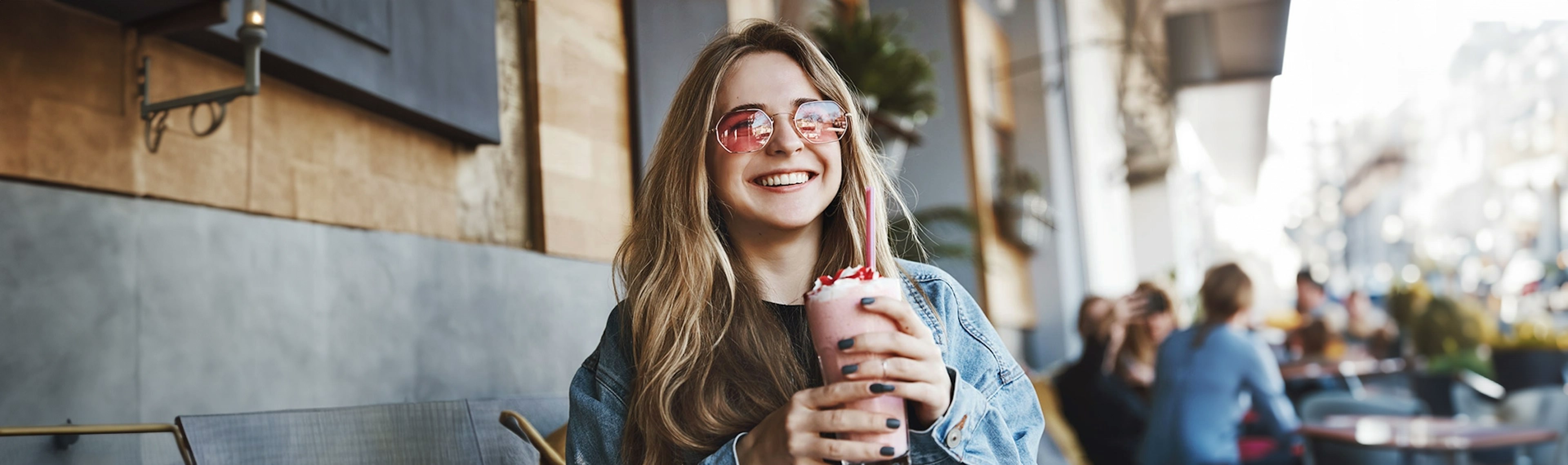 A smiling woman with sunglasses and a pink shake