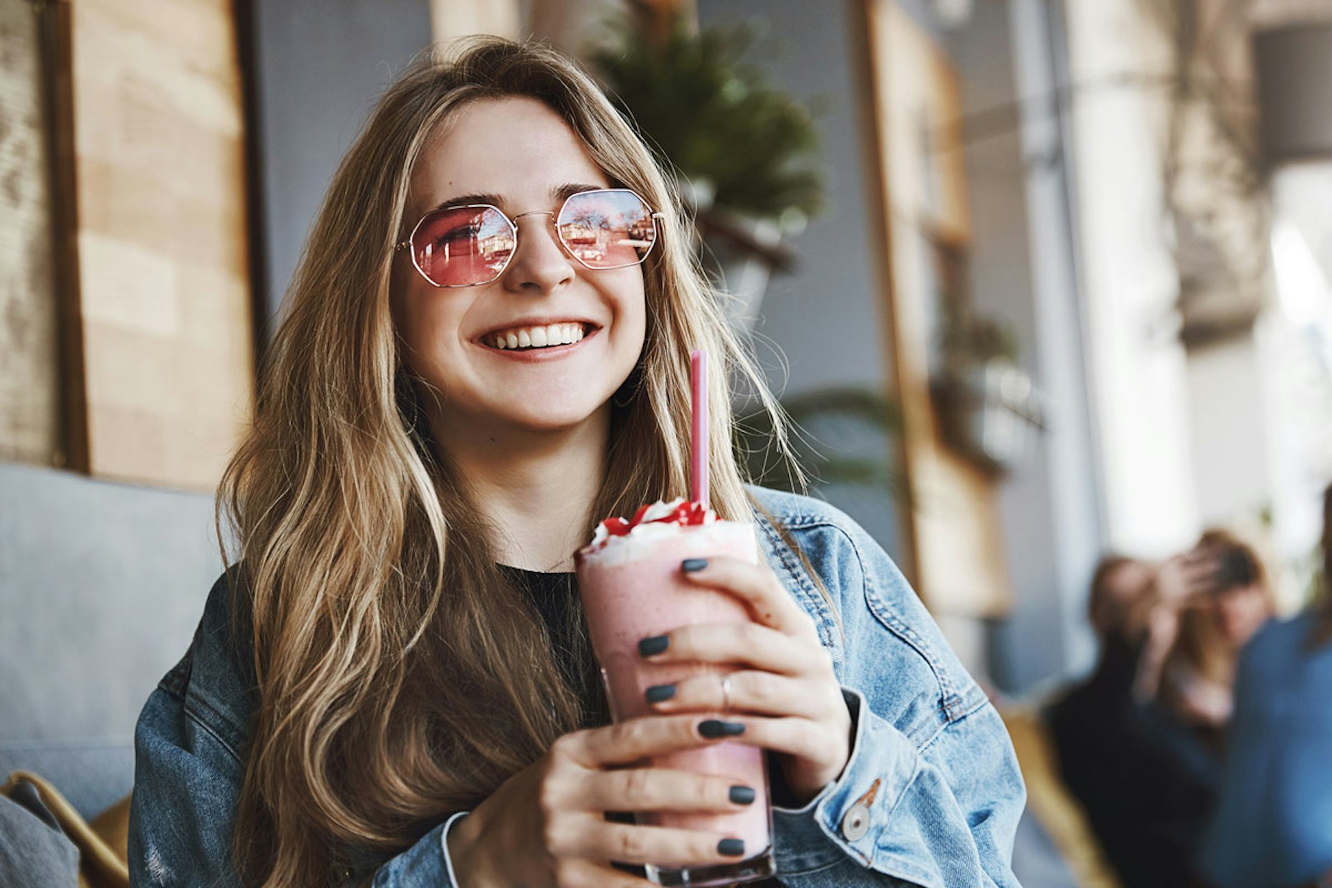 A smiling woman with sunglasses and a pink shake