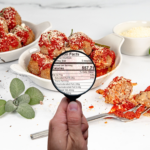 Hand with magnifying glass in front of meatballs