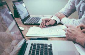 Closeup of desk with coworkers working on research together for keto research roundup article